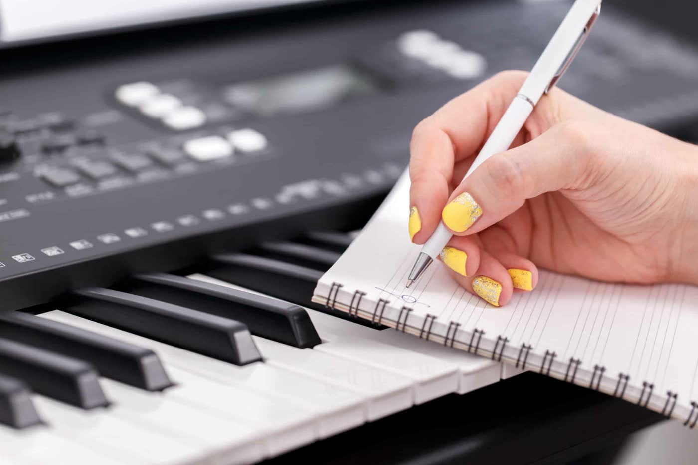 Escribiendo una letra en una libreta apoyada sobre el teclado
